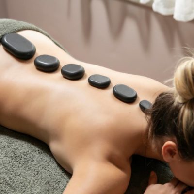 Ξαπλωμένη ξανθιά γυναίκα που της κάνουν hot stone μασάζ